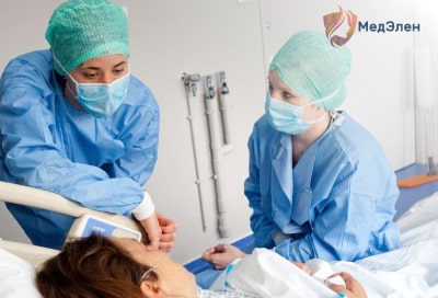 Два врача у койки с пациенткой